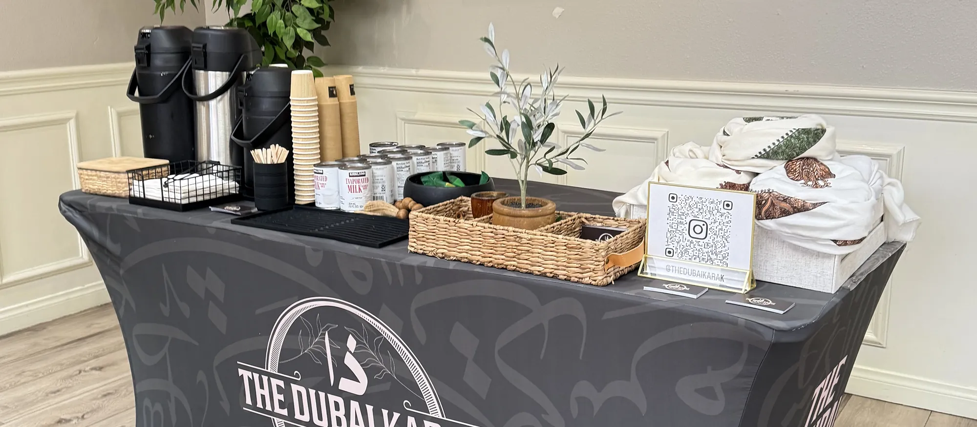 The Dubai Karak black branded table set up indoors with brewing equipment and cups