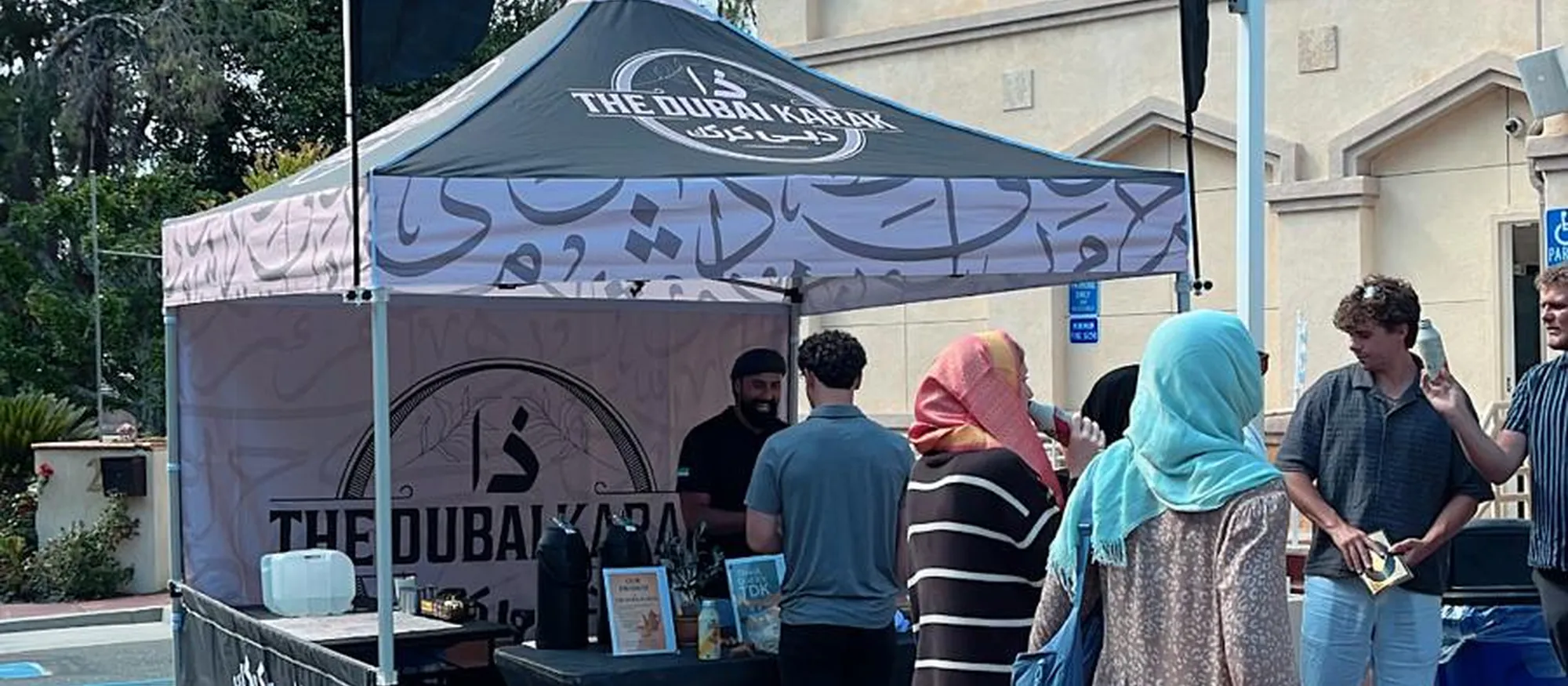 Guests being served karak chai at The Dubai Karak booth outside a community centre