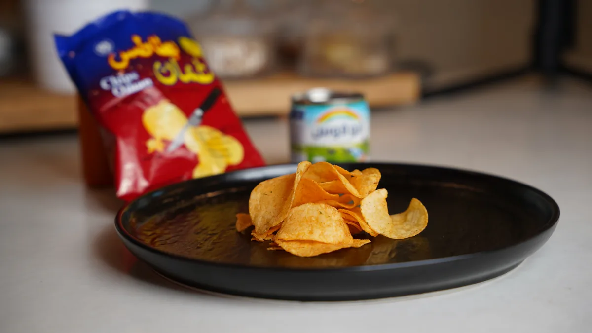 Chips Oman crisps served on a black plate alongside the bag