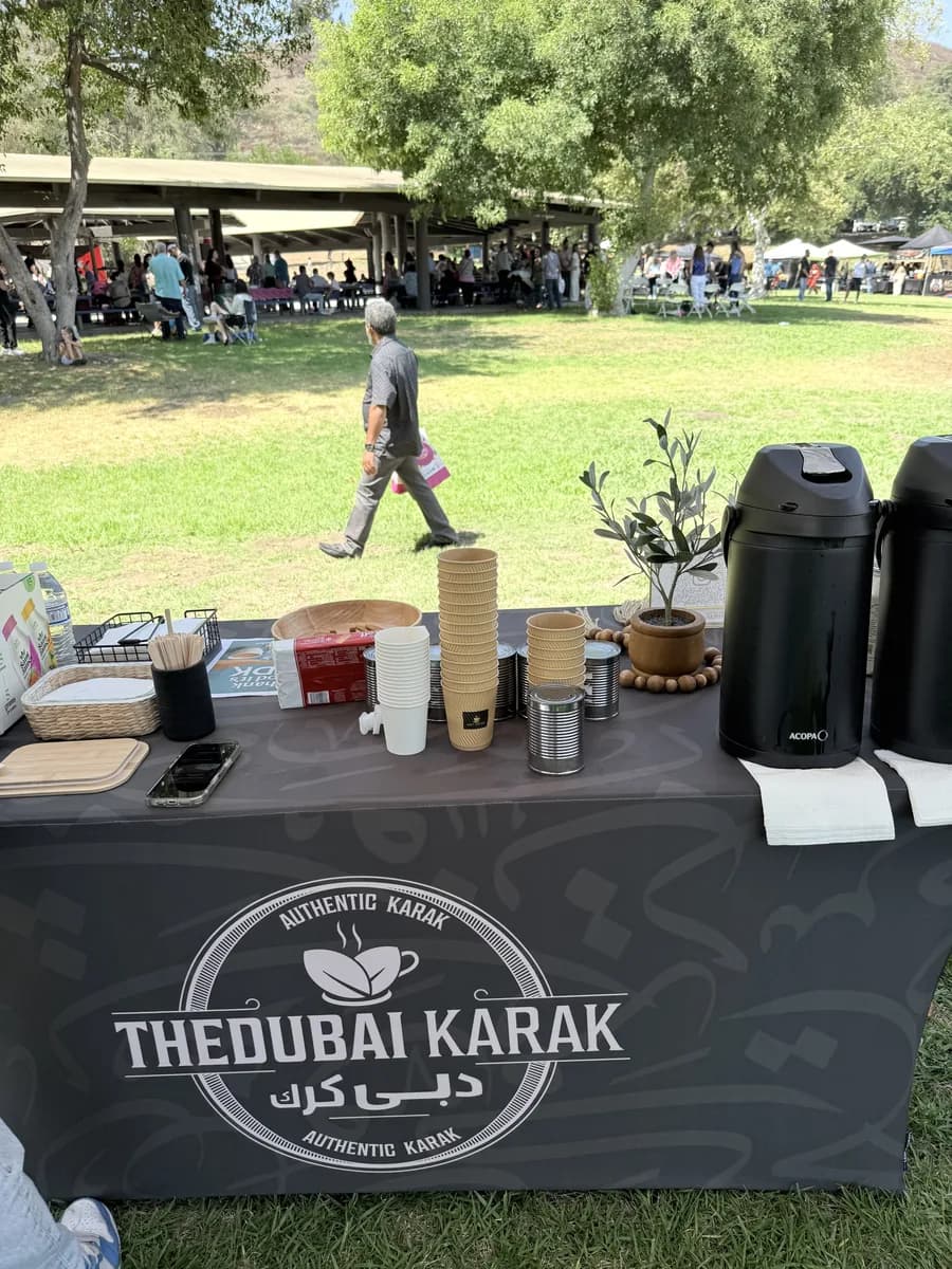The Dubai Karak serving table at an outdoor park event with guests in the background
